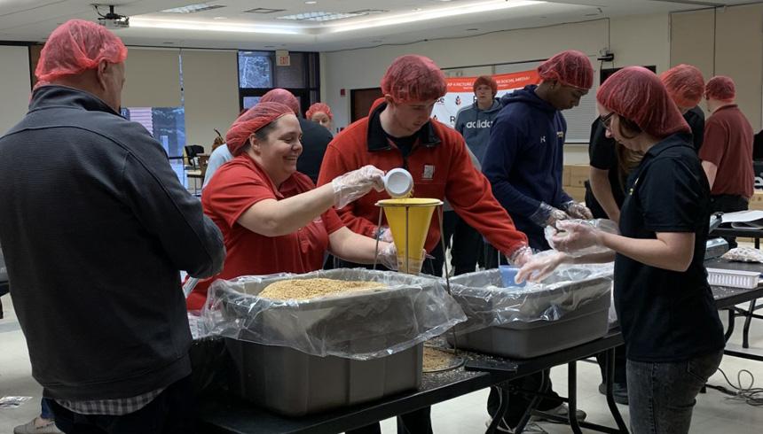 Students volunteer their time to help pack boxes of food to give away to those in need.