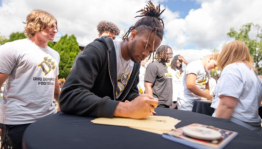 A student is filling out a paper form while attending Convocation.