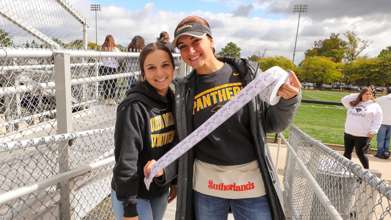 Two students holding a roll of tickets smile for the camera.