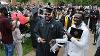 Smiling graduates holding their degrees exit the Erskine Oval during the Recessional.